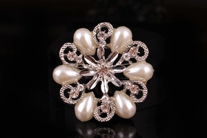 Dettaglio macro di spilla a fiore argento con perle e strass brillanti incastonati