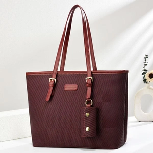 Dettaglio della borsa tote rosso vino con trama intrecciata, doppi manici e mini pochette