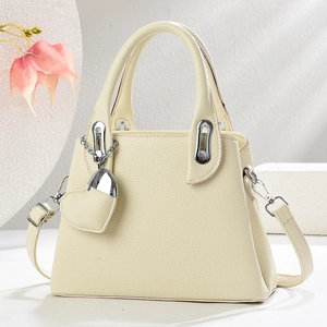 Detail of cream lychee texture leather handbag with silver clasp and heart charm