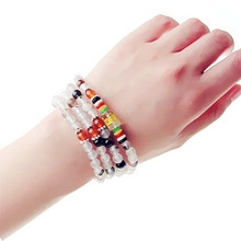 Detail of multi-layer beaded bracelet featuring colorful round beads on a model wrist