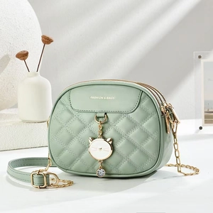 Détail du sac matelassé vert menthe avec pendentif chat et chaîne dorée