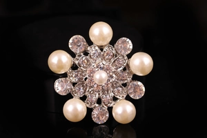 Vista macro di una spilla a fiore argento con perle bianche e strass di cristallo lucido