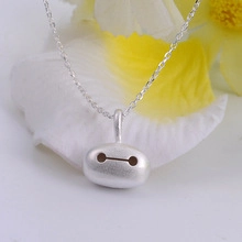 Macro view of a silver robot pendant necklace on elegant floral background