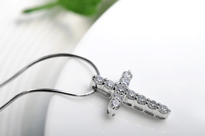 Macro detail of silver cross pendant with sparkling zircons and smooth snake chain