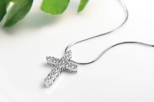 Close-up of a silver cross pendant featuring sparkling cubic zirconia on a snake chain