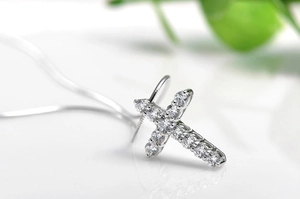 Close-up of a silver cross pendant featuring sparkling diamonds on a delicate chain