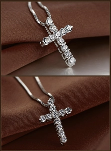 Macro shot of silver cross pendant with pavé set cubic zirconia on brown satin