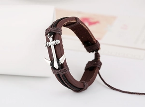 Detail showing vintage multilayer braided leather bracelet with a silver anchor charm