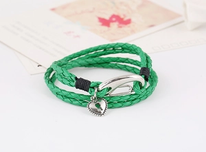 Macro shot of green braided leather bracelet featuring a silver heart-shaped padlock charm