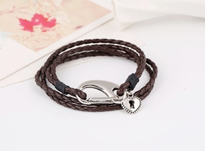 Close-up of brown braided leather bracelet with silver heart lock charm and lobster clasp