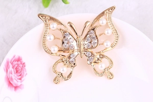 Detailed shot of gold hollow butterfly brooch with pearls and inlaid rhinestones