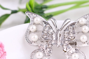 Macro shot of silver hollow butterfly brooch with sparkling crystals and pearls