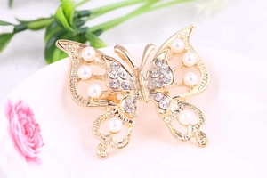 Close-up of golden hollow butterfly brooch with pearls and shimmering rhinestones