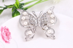 Close-up of hollow butterfly brooch with pearls and crystals on decorative porcelain