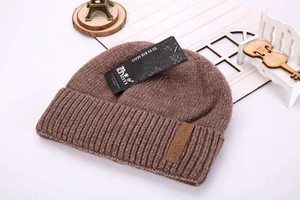 Close-up of thick coffee brown knit beanie with leather patch and texture details