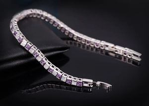Détail macro d'un bracelet de tennis argenté serti de zircons violets et blancs