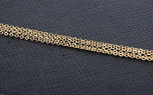 Macro detail of golden chain link necklace with polished finish on black leather surface