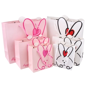 Pink and white paper gift bags with bunny ears and Happy lettering in various sizes