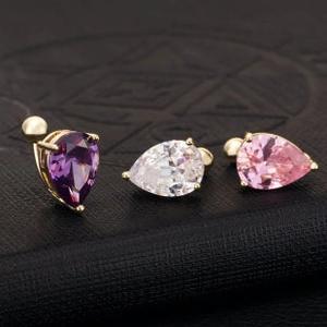 Macro view of teardrop zircon studs in purple, white, and pink with golden claw settings