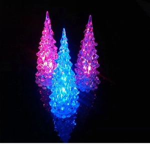 Close-up of crystal mini Christmas trees with colorful LED lights on black background
