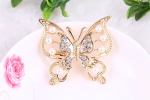 Detail showing vintage hollow butterfly brooch with pearls and rhinestones on ceramic