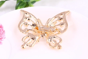 Detailed back view of hollow butterfly brooch showing secure safety pin and golden texture