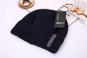 Detail of navy blue cable knit beanie with thick double layer and gray rectangle patch