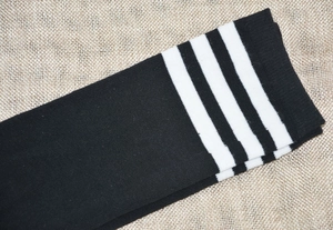 Detail of black knee high socks with three white stripes in a sporty varsity style