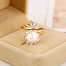 Detail macro-opname van de gouden open ring met grote witte parel en kristallen accenten