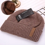 Detail of coffee brown knit hat showing thick faux fur lining and leather patch