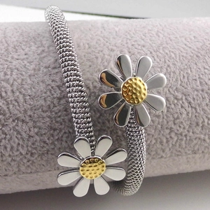Macro shot of a flexible silver mesh bangle featuring dual daisy accents with gold centers