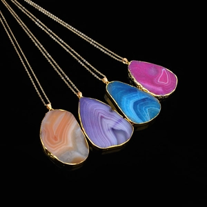 Close-up of agate slice pendants with gold edges and colorful band textures on black mirror