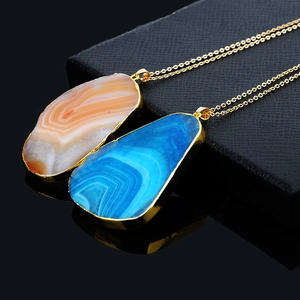 Close-up of vibrant orange and blue agate slice pendants with gold plated edges