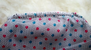 Detailed view of gray fabric coin purse with red blue dots and neat edge stitching