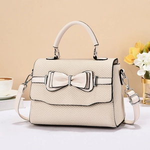 Close-up of woven texture and double leather bow detail on beige luxury crossbody bag