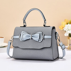 Detail of grey-blue luxury crossbody bag with layered bow and textured fabric finish