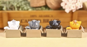 Detailed macro view of four miniature 3D cartoon cats sitting in boxes for keychains