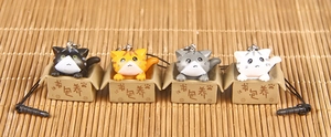 Detailed view of four 3D cartoon cat keychains emerging from miniature cardboard boxes