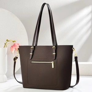 Dettaglio della trama intrecciata e finiture dorate su borsa tote marrone con zip posteriore