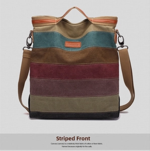 Front view detail of a multi-color striped canvas handbag with leather handles and logo
