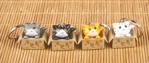 Close-up of four cute 3D resin cats in boxes as cartoon keychains on bamboo mat