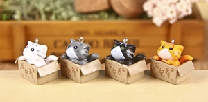 Detail of four colorful 3D cartoon cat keychains in miniature boxes on wooden background