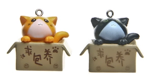 Detailed view of 3D cartoon cats in boxes with orange and black keychain designs