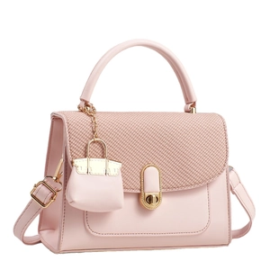 Pink leather handbag with woven flap and gold twist lock in minimalist studio setting