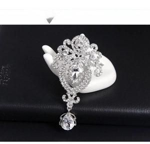 Close-up of crystal crown brooch with pear-shaped rhinestones on a white hand model