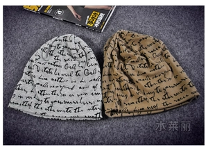 Detail of grey and khaki slouchy beanies with black cursive script print fabric