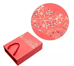 Close-up of Chinese style red gift bag with gold floral patterns and ribbon handles