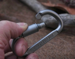 Macro detail of a grey aluminum alloy carabiner with a secure screw lock and safety warning