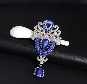 Detail of silver crown brooch with blue teardrop crystals and vintage openwork pattern