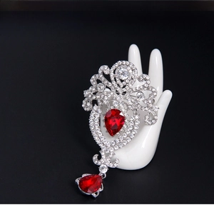 Baroque crown brooch detail with red pear-shaped rhinestones on silver metal